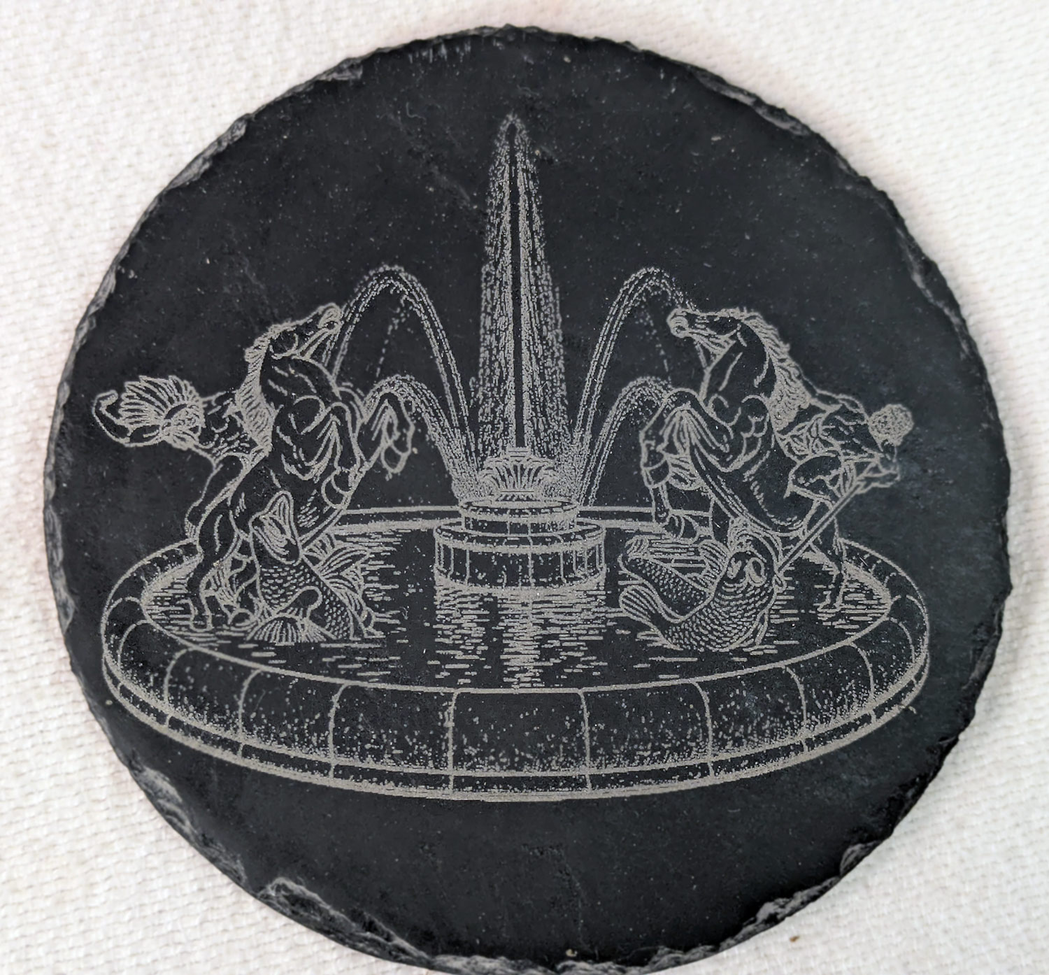 Fountain artwork engraved on a round slate coaster